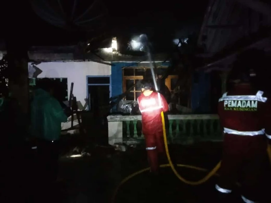PADAMKAN API. Petugas UPT Damkar Kuningan berusaha memadamkan api yang menghanguskan rumah Desti, warga Desa/Kecamatan Cibeureum, Minggu malam.
