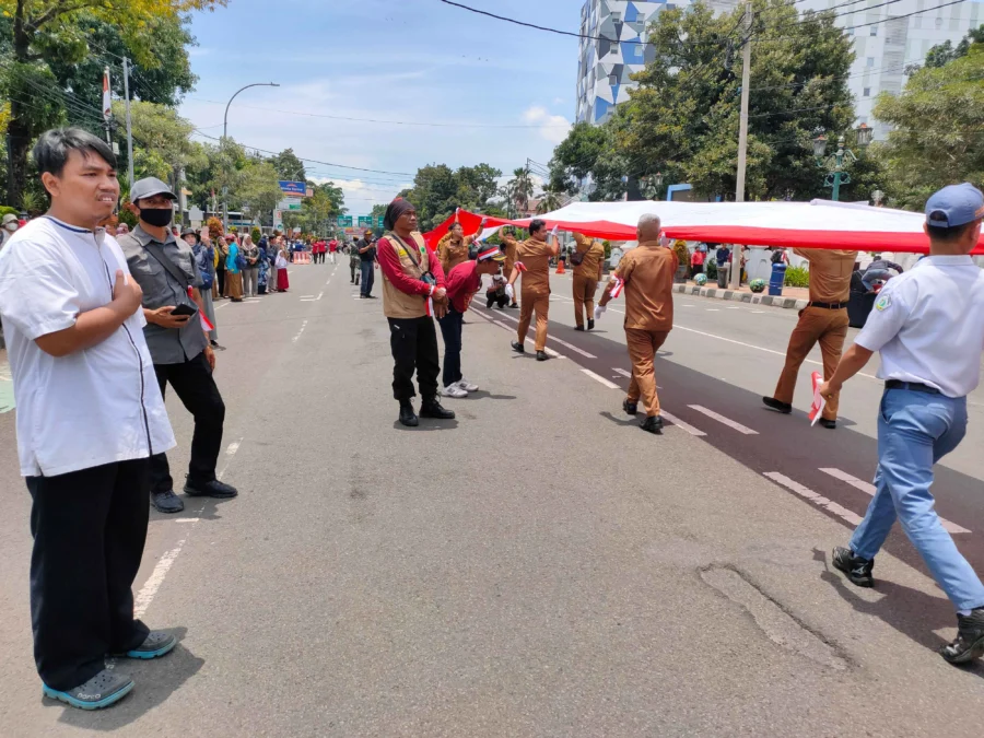 PENGHORMATAN. Salah seorang warga Kota Cirebon, mempunyai cara tersendiri untuk menghormati bendera pusaka merah putih sepanjang 500 meter yang dibawa pasukan gabungan pada Kirab Merah Putih, Senin  6 Maret 2023. FOTO: ASEP SAEPUL MIELAH/RAKYAT CIREBON